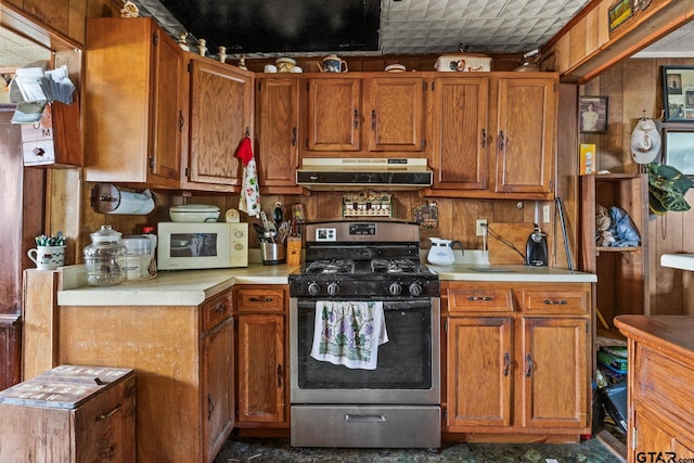 500 W Mclean St, Talco, TX 75487 - kitchen featuring gas stove, white microwave, under cabinet range hood, light countertops, and brown cabinetry