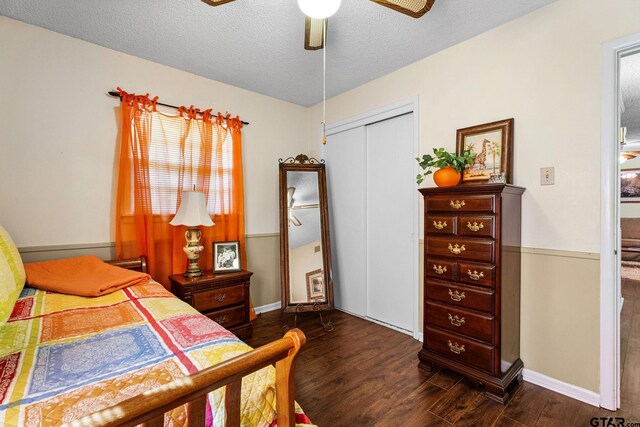 bedroom with a textured ceiling, dark wood-type flooring, ceiling fan, and a closet