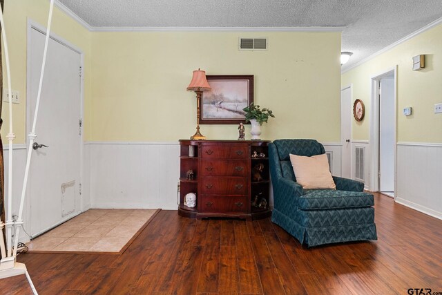 sitting room featuring a textured ceiling, hardwood / wood-style flooring, and crown molding