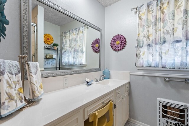 bathroom with vanity, an enclosed shower, heating unit, and a textured ceiling