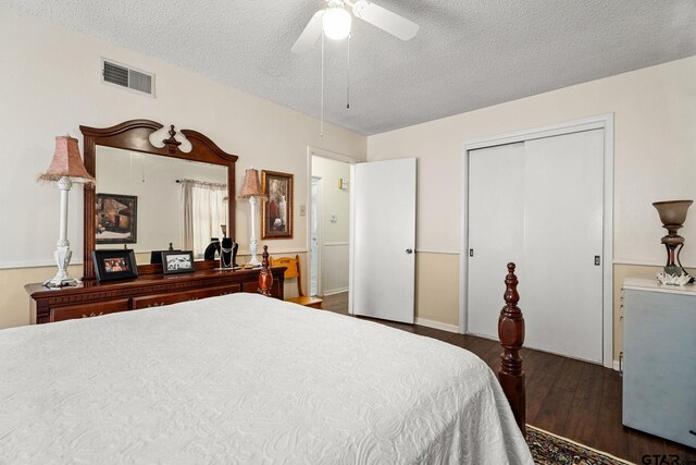 bedroom with dark wood-type flooring, a closet, a textured ceiling, and ceiling fan