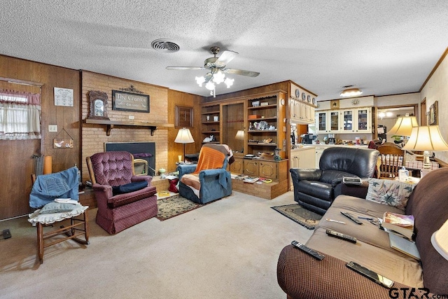 living room featuring ceiling fan, wooden walls, a fireplace, a textured ceiling, and light colored carpet