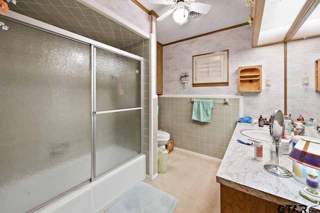 full bathroom with combined bath / shower with glass door, tile walls, vanity, a textured ceiling, and toilet