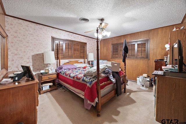 carpeted bedroom with ceiling fan, ornamental molding, and a textured ceiling