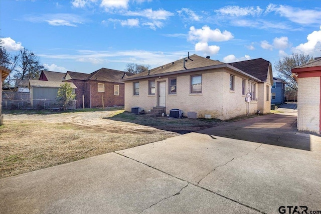 rear view of house with brick siding, a yard, entry steps, fence, and cooling unit