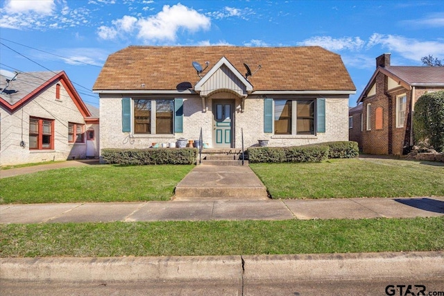 bungalow-style house featuring brick siding and a front yard