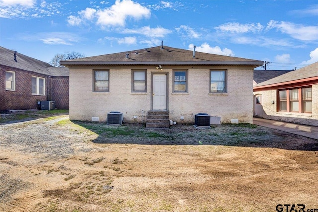 rear view of property with entry steps, brick siding, and central AC unit