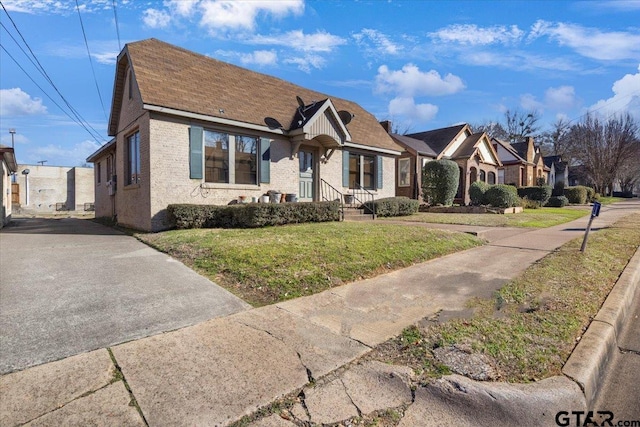 view of front of house featuring brick siding, a front yard, and a residential view