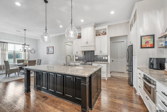 7306 Tule Creek Ln, Tyler, TX 75703 - kitchen with stainless steel appliances, white cabinets, tasteful backsplash, crown molding, and a kitchen island with sink