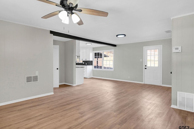 unfurnished living room with ceiling fan, light hardwood / wood-style floors, sink, beamed ceiling, and crown molding