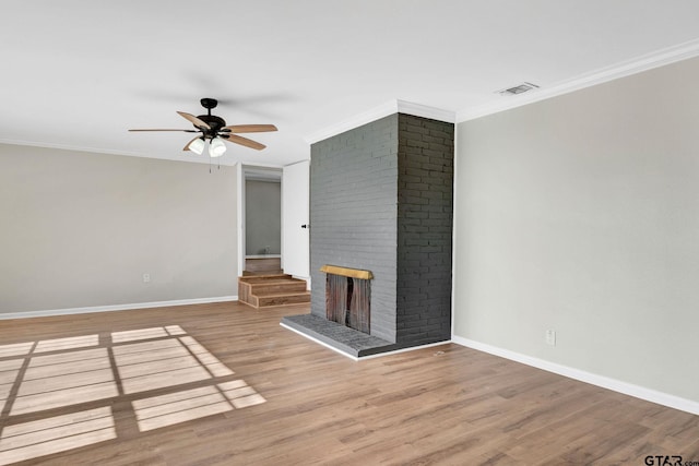 unfurnished living room featuring ceiling fan, wood-type flooring, ornamental molding, and a fireplace