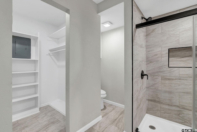 bathroom with toilet, electric panel, and tiled shower