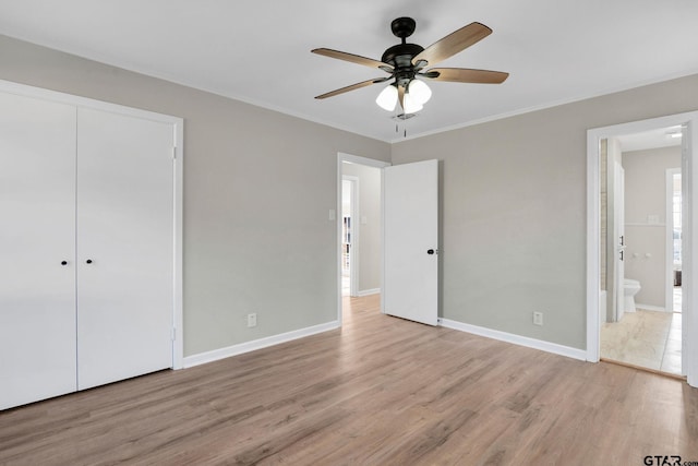 unfurnished bedroom featuring ensuite bath, a closet, ceiling fan, light hardwood / wood-style flooring, and crown molding