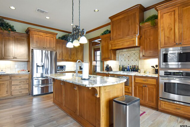 1860 Holcomb Cir, Tyler, TX 75703 - kitchen with brown cabinetry, visible vents, a sink, stainless steel appliances, and light wood-type flooring
