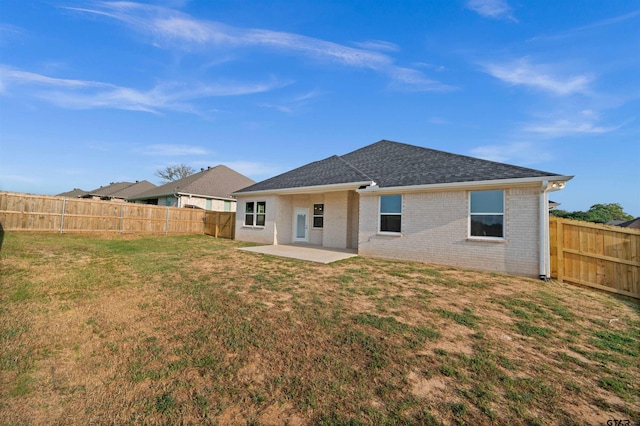 rear view of house with a lawn, a patio, brick siding, and a fenced backyard