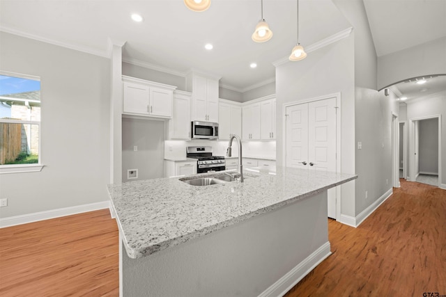 kitchen with appliances with stainless steel finishes, arched walkways, a sink, ornamental molding, and white cabinetry