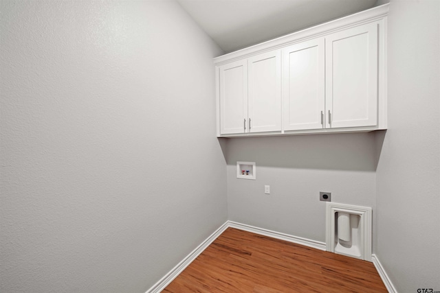 clothes washing area with washer hookup, electric dryer hookup, cabinet space, wood finished floors, and baseboards
