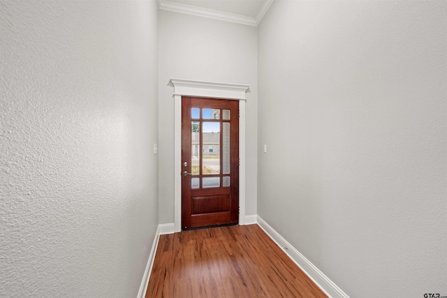 doorway with baseboards, ornamental molding, and wood finished floors