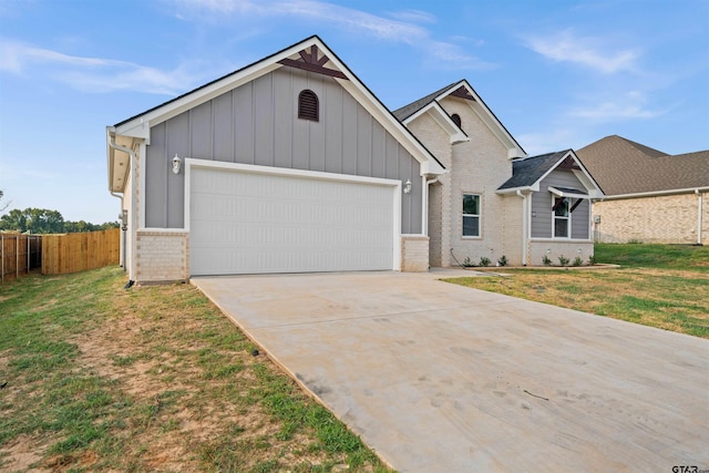 view of front of house featuring fence, a front lawn, brick siding, a garage, and driveway