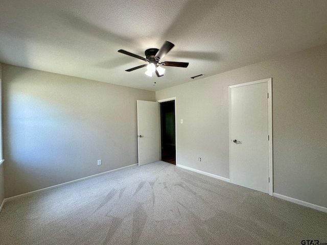 unfurnished bedroom featuring carpet, a ceiling fan, a textured ceiling, and baseboards