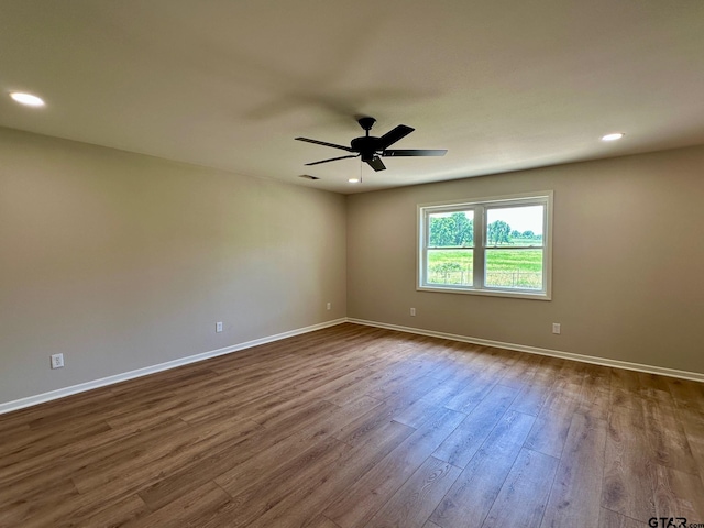 spare room featuring dark wood-type flooring, a ceiling fan, recessed lighting, and baseboards