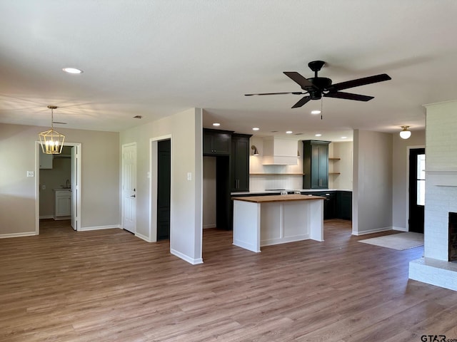 kitchen featuring open shelves, baseboards, open floor plan, light wood-type flooring, and a brick fireplace