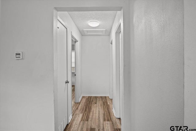 hallway with hardwood / wood-style floors and a textured ceiling