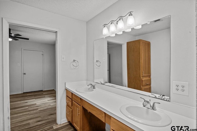 bathroom with a textured ceiling, vanity, hardwood / wood-style flooring, and ceiling fan