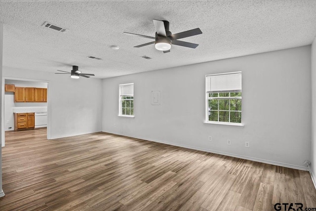 unfurnished living room with a textured ceiling, hardwood / wood-style floors, and a healthy amount of sunlight