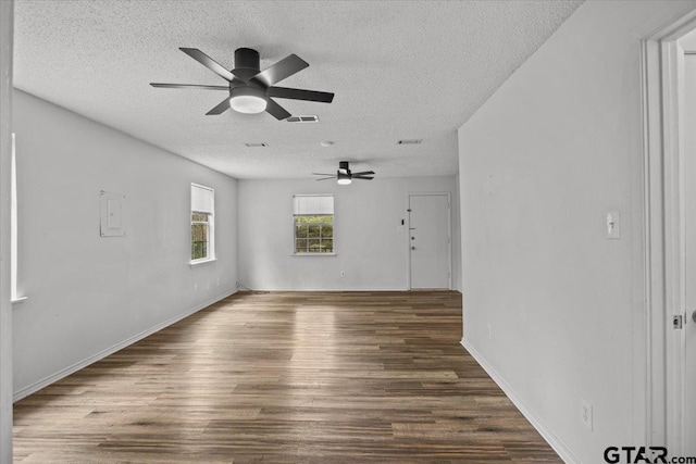 empty room with a textured ceiling, dark hardwood / wood-style floors, and ceiling fan