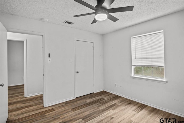 unfurnished bedroom featuring a textured ceiling, ceiling fan, dark hardwood / wood-style floors, and a closet