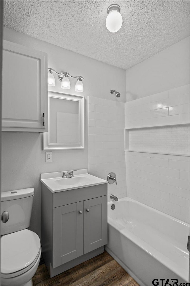 full bathroom featuring vanity, a textured ceiling, shower / bathing tub combination, hardwood / wood-style floors, and toilet