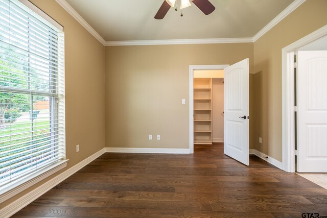 936 Cambridge Bnd, Tyler, TX 75703 - unfurnished bedroom featuring a walk in closet, dark wood-type flooring, crown molding, baseboards, and a ceiling fan