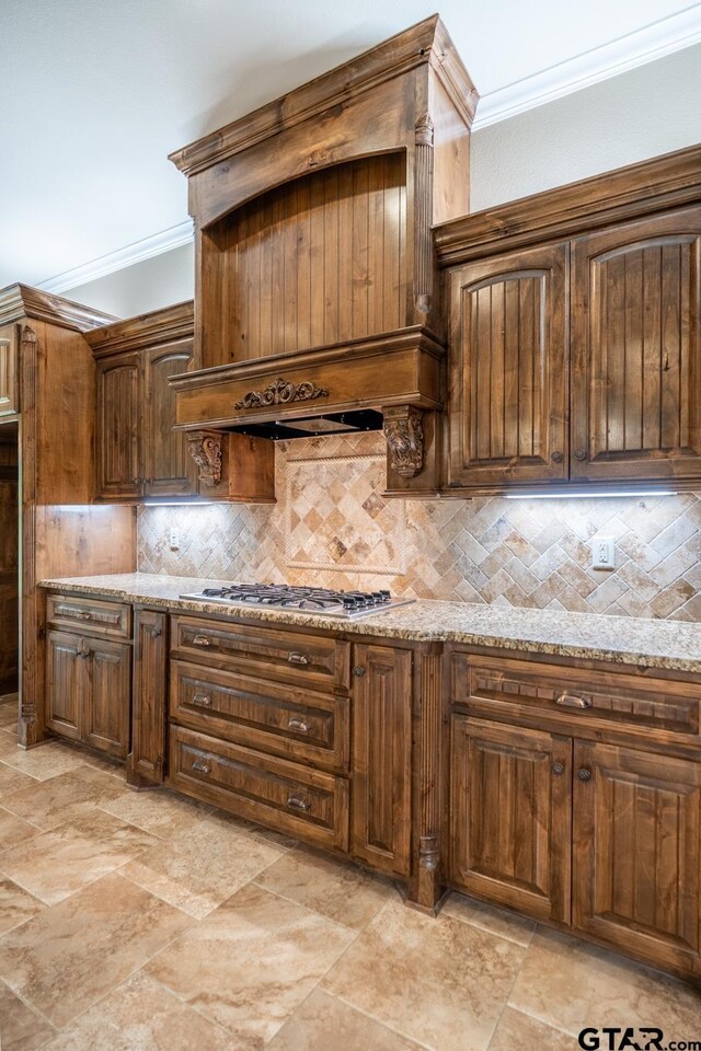 936 Cambridge Bnd, Tyler, TX 75703 - kitchen with crown molding, tasteful backsplash, stainless steel gas cooktop, premium range hood, and light stone countertops