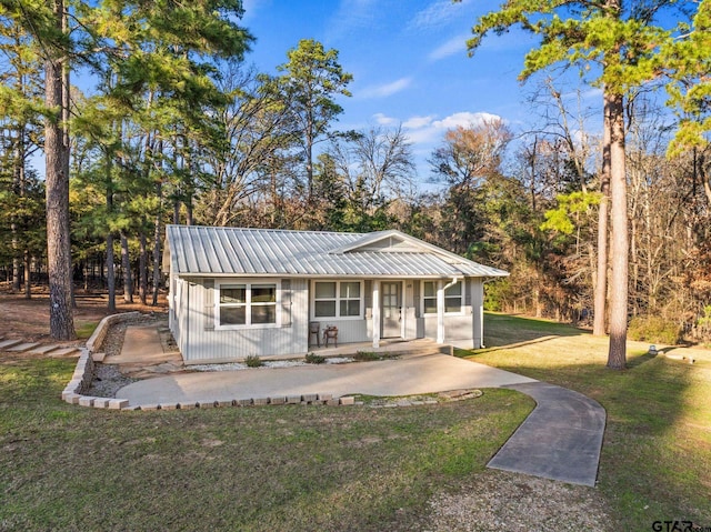 view of front facade featuring metal roof, covered porch, and a front lawn