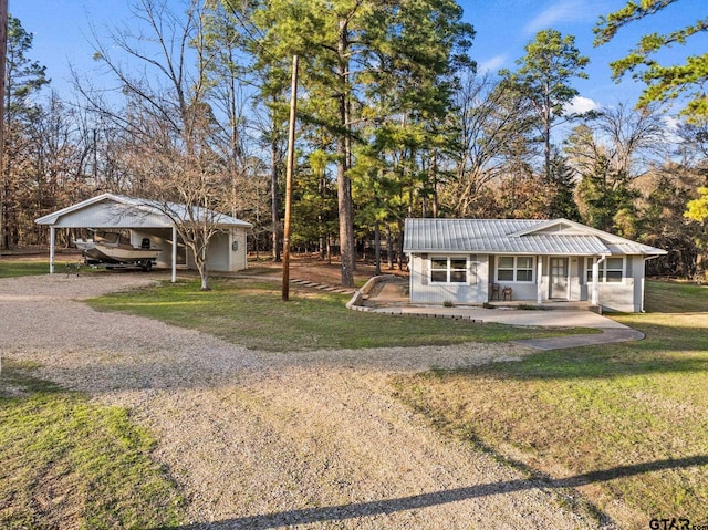 view of front of house with covered porch, a detached carport, metal roof, and a front yard