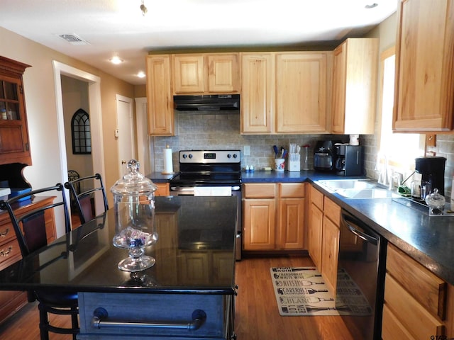 kitchen featuring visible vents, under cabinet range hood, a sink, dark countertops, and dishwasher