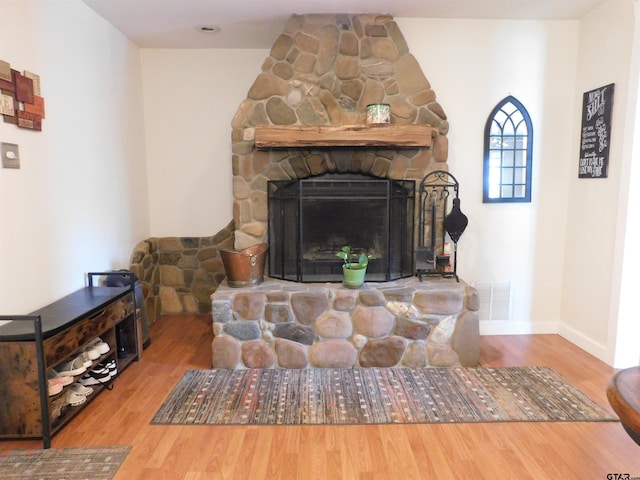 room details with visible vents, a fireplace, baseboards, and wood finished floors