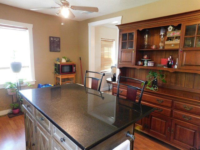 kitchen with a ceiling fan, wood finished floors, baseboards, open shelves, and glass insert cabinets