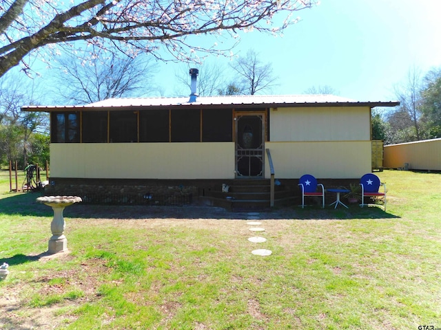 rear view of property featuring a lawn, entry steps, and metal roof