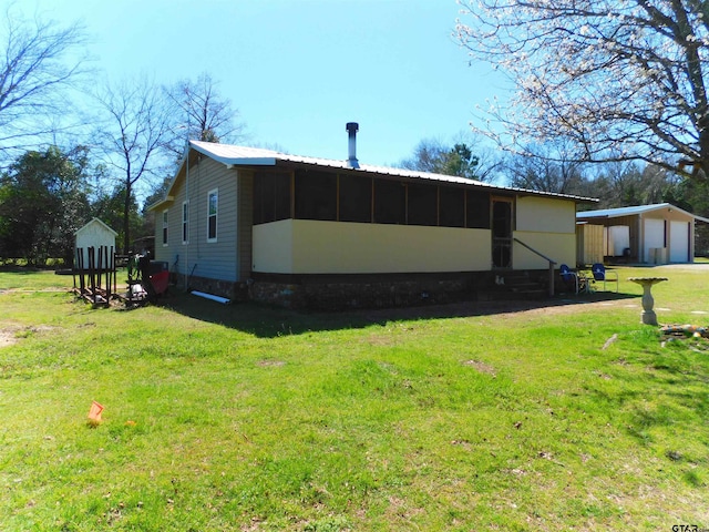 exterior space with a garage, a yard, an outdoor structure, metal roof, and a carport