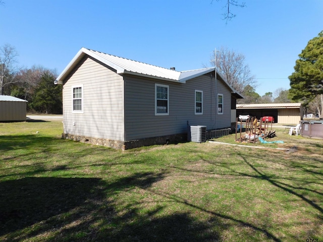 back of property with crawl space, a yard, central AC unit, and metal roof