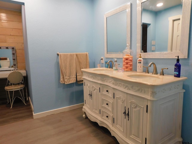 full bath featuring a sink, baseboards, wood finished floors, and double vanity