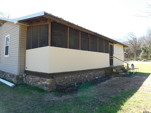 view of property exterior featuring metal roof, a sunroom, and entry steps