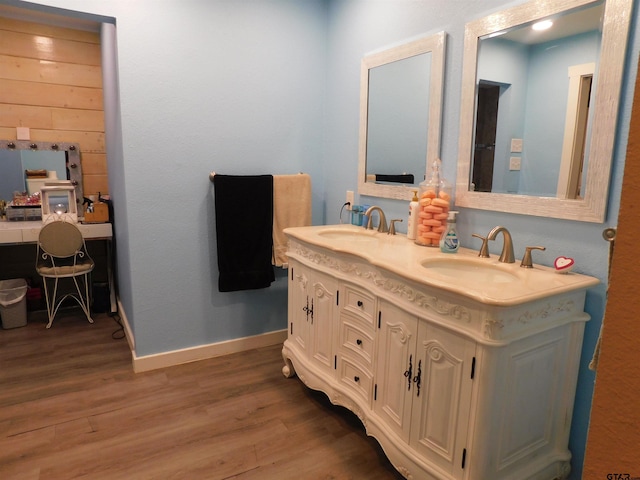 full bathroom featuring double vanity, wood finished floors, baseboards, and a sink