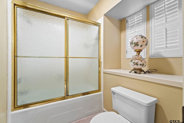 bathroom featuring bath / shower combo with glass door and toilet