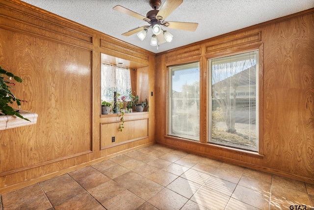 spare room featuring ceiling fan, a textured ceiling, and wooden walls