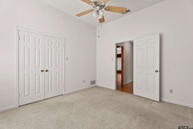 unfurnished bedroom with light carpet, a textured ceiling, a closet, and ceiling fan