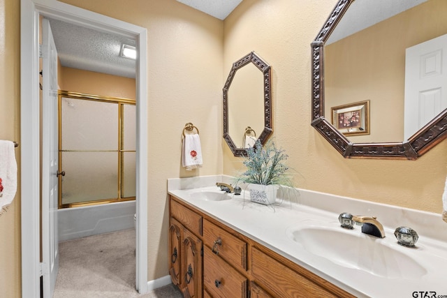 bathroom with vanity, combined bath / shower with glass door, and a textured ceiling