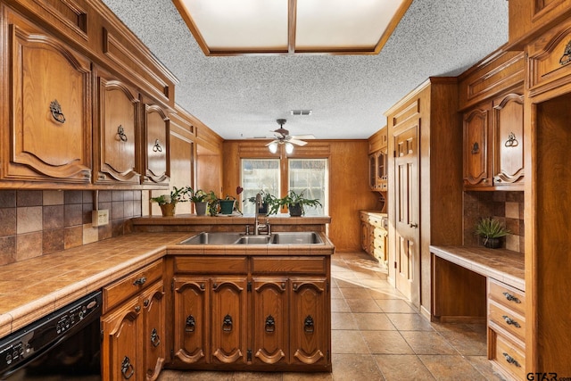 kitchen with built in desk, dishwasher, sink, tile counters, and ceiling fan